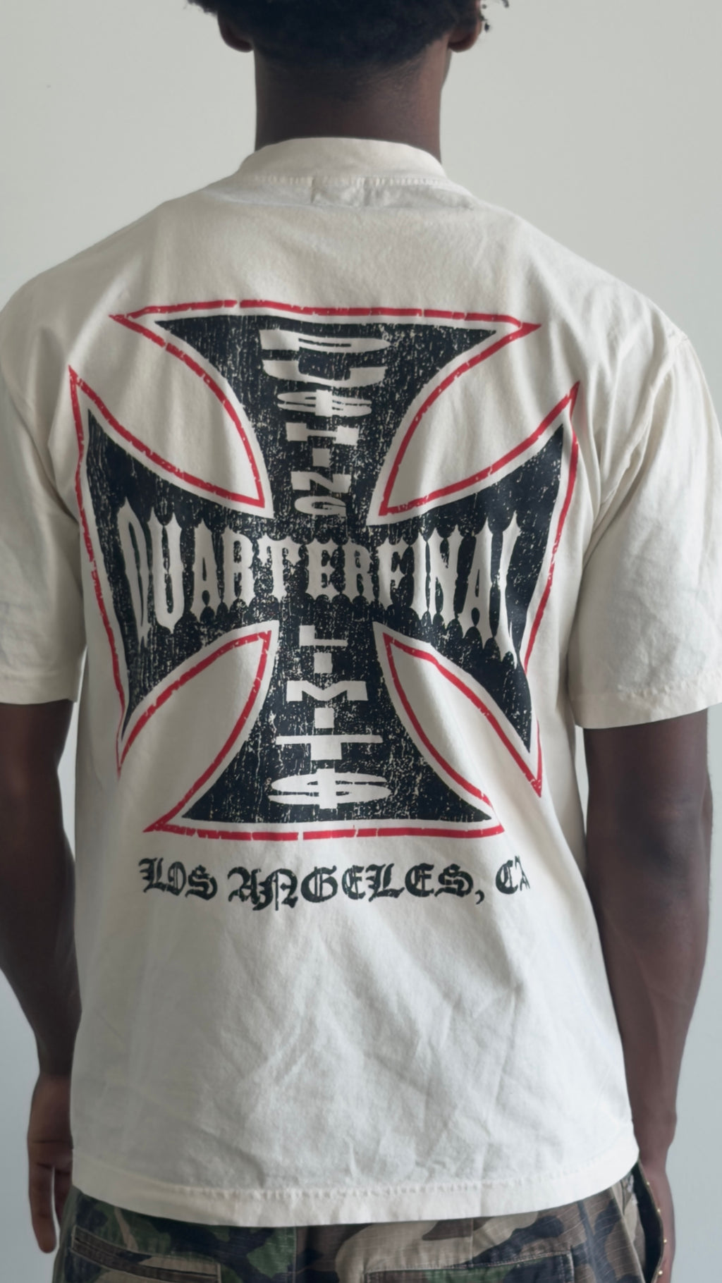 A person shown from the back wearing a cream-colored t-shirt with a large black and red distressed graphic on the back. The graphic features the text '2023 QUARTERFINAL LFA' and 'LOS ANGELES, CA'.